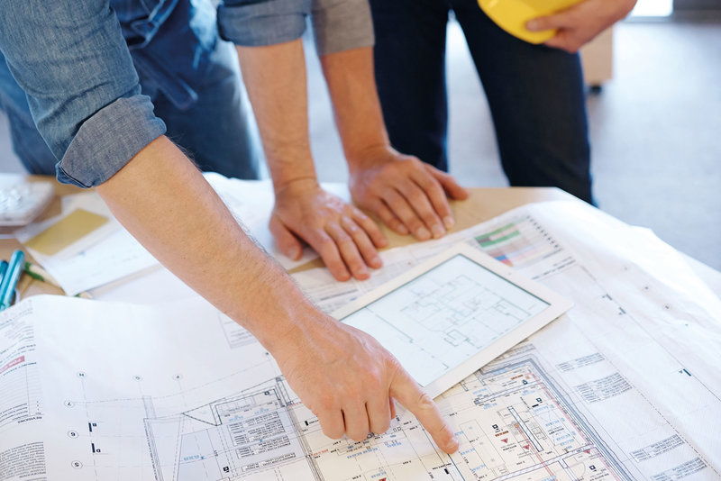 Bauen mit Mammen Bauleiter beraten sich über einem Bauplan